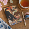 Carnet chat noir kawaii sur un bureau avec du the