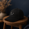Casquette chat noir sur un tabouret, mur bleu nuit