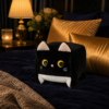 Coussin chat noir kawaii sur un lit bleu nuit