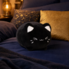 Peluche chat noir kawaii sur un lit bleu nuit