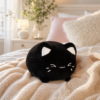 Peluche chat noir kawaii sur un lit cosy
