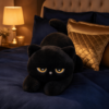 Peluche chat noir ronde sur un lit bleu nuit