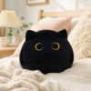 Peluche chat noir ronde sur un lit