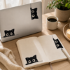 Stickers chat noir espiegles sur un laptop et un carnet