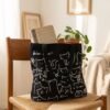 Tote bag chat noir pose sur une chaise